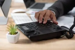 partial view of businessman dialing on voip phone, blurred foreground
